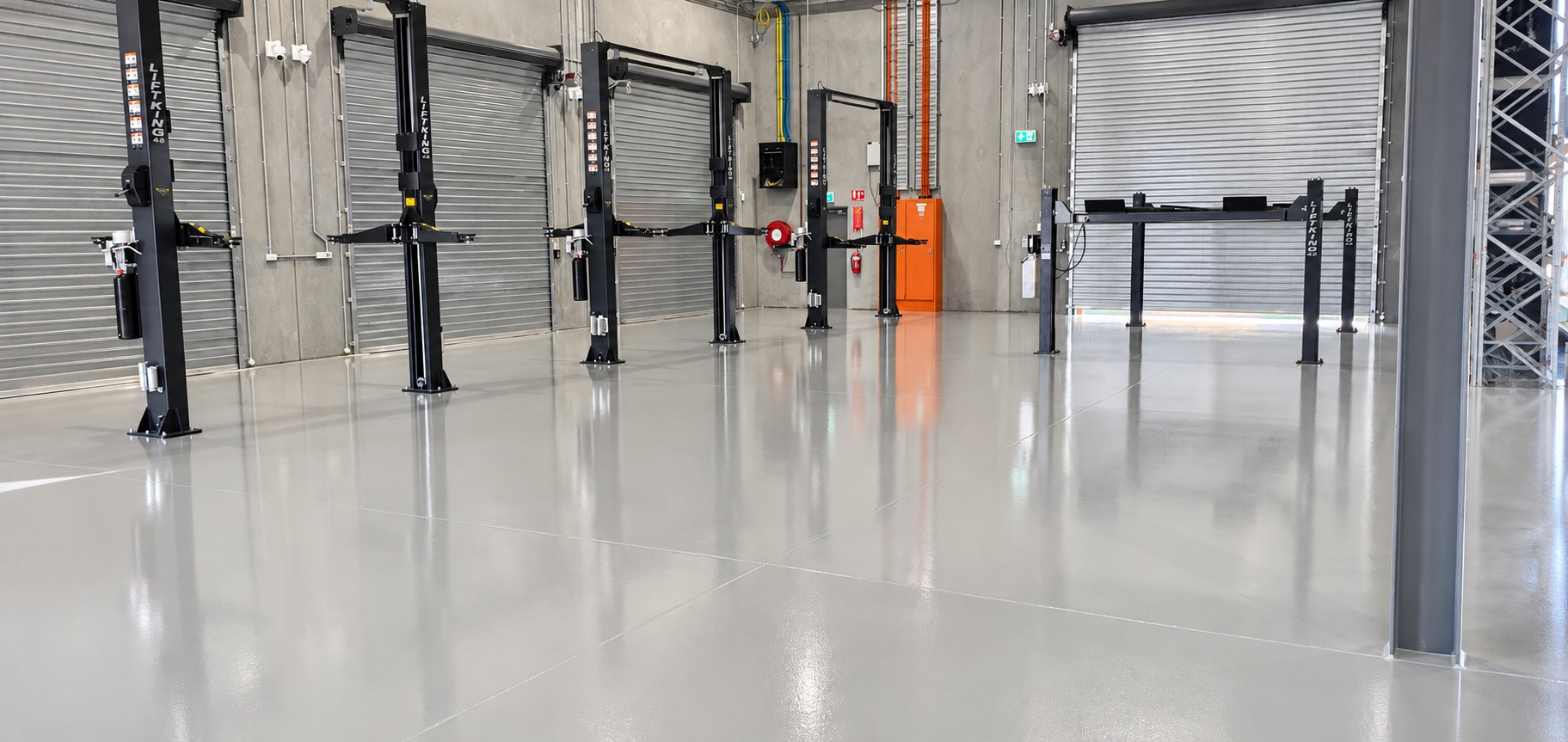 Grey industrial epoxy floor between workshop vehicle lifts